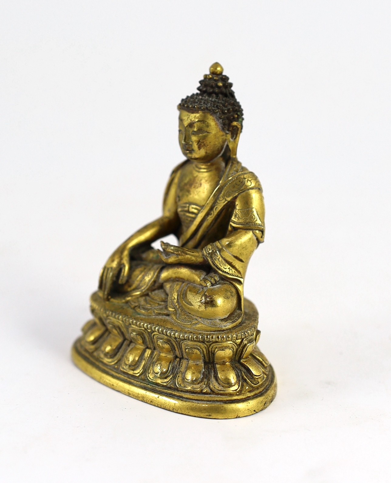 A small Tibetan gilt bronze seated figure of Buddha Shakyamuni, 18th century, 9.5cm high, lacking bowl in left hand